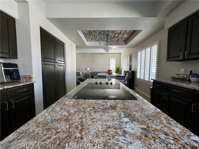 kitchen featuring black electric stovetop, a textured ceiling, and a raised ceiling