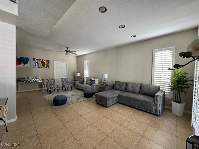 living room featuring a textured ceiling, light tile patterned floors, and ceiling fan