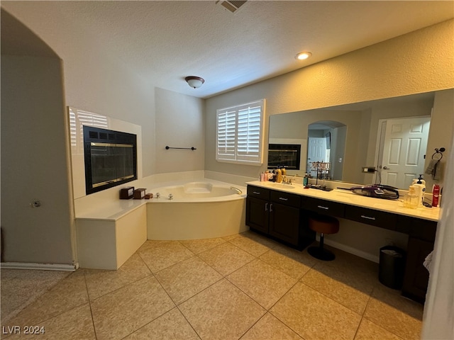 bathroom with vanity, a textured ceiling, a washtub, and tile patterned flooring