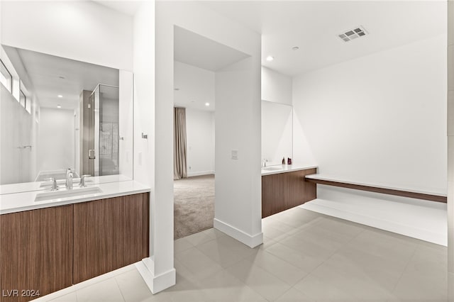 bathroom with a shower with door, vanity, and tile patterned floors