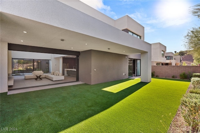 back of property featuring a patio, an outdoor living space, and a lawn