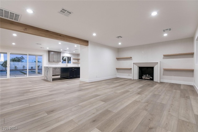 unfurnished living room with beam ceiling and light hardwood / wood-style flooring