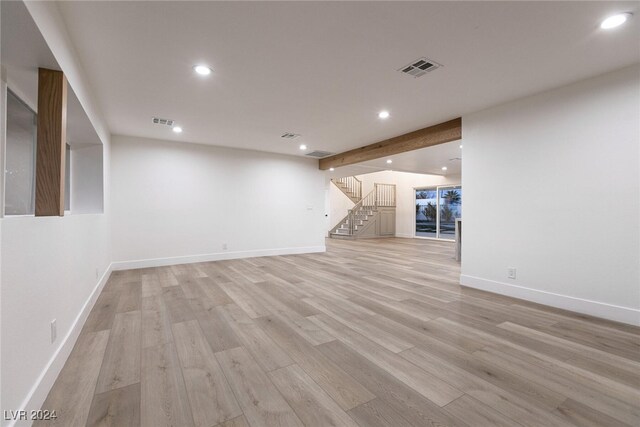 unfurnished living room with beamed ceiling and light wood-type flooring