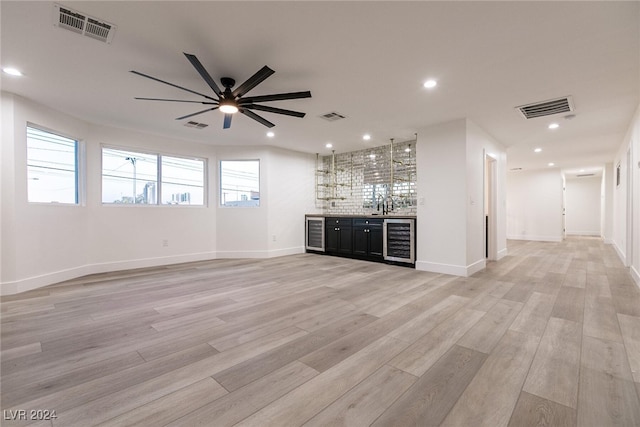 unfurnished living room with ceiling fan, wine cooler, and light hardwood / wood-style floors