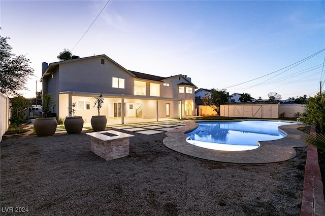 pool at dusk with a patio area