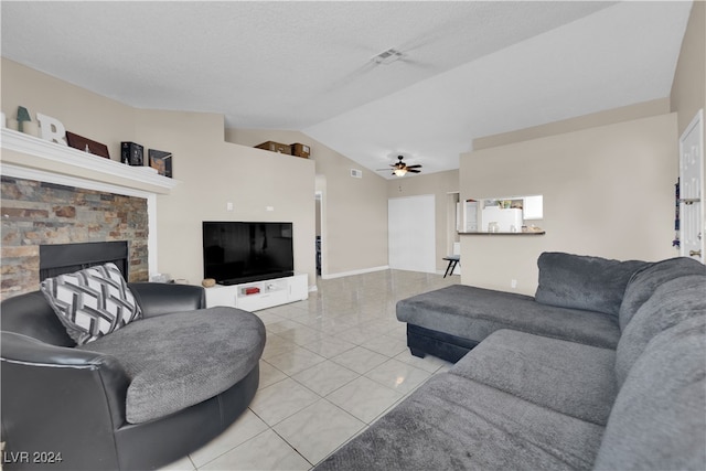 tiled living room featuring vaulted ceiling, ceiling fan, a fireplace, and a textured ceiling