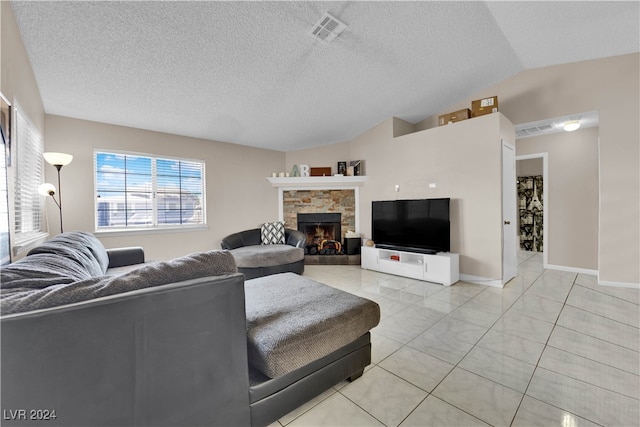 living room featuring vaulted ceiling, a textured ceiling, light tile patterned flooring, and a stone fireplace