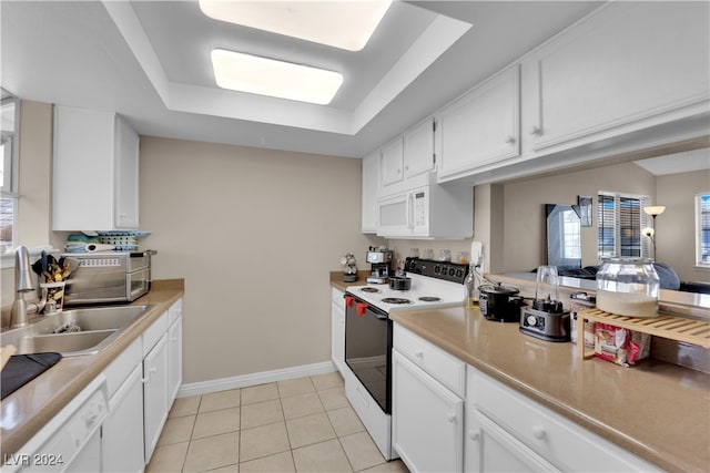 kitchen with light tile patterned flooring, sink, white cabinetry, white appliances, and a raised ceiling