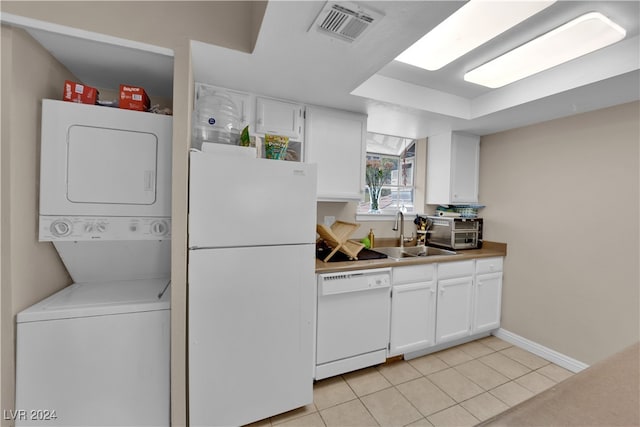 kitchen featuring sink, white appliances, white cabinetry, and stacked washing maching and dryer