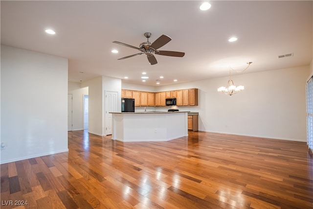 unfurnished living room featuring ceiling fan with notable chandelier and light hardwood / wood-style floors