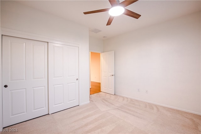 unfurnished bedroom featuring light carpet, a closet, and ceiling fan