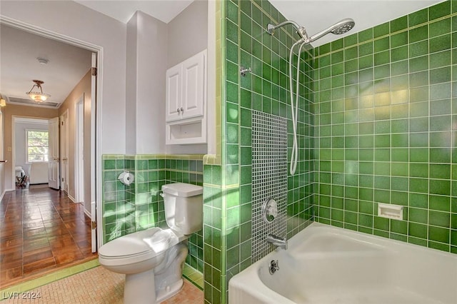 bathroom with tile patterned floors, toilet, tile walls, and tiled shower / bath