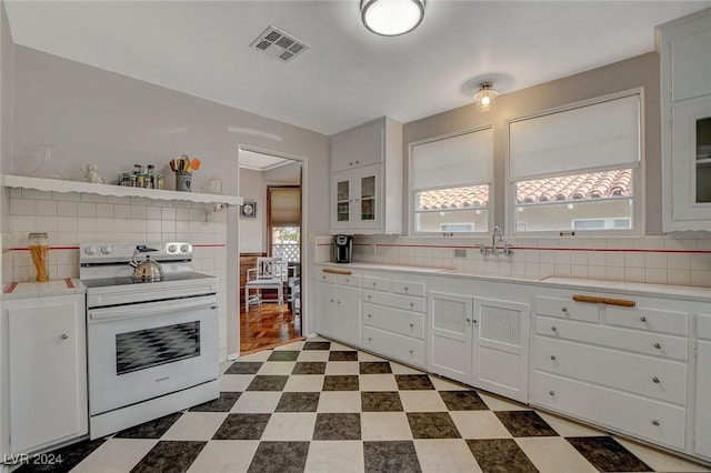 kitchen with white cabinets, range with electric cooktop, and tasteful backsplash