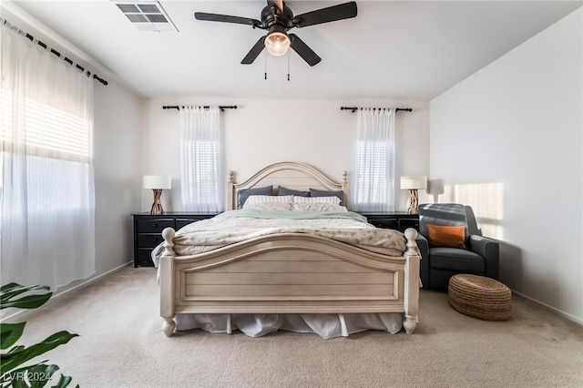 carpeted bedroom featuring multiple windows and ceiling fan