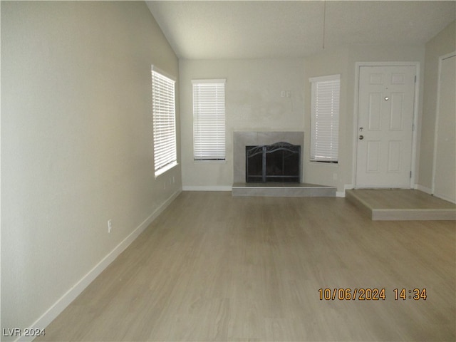 unfurnished living room featuring vaulted ceiling and light hardwood / wood-style flooring