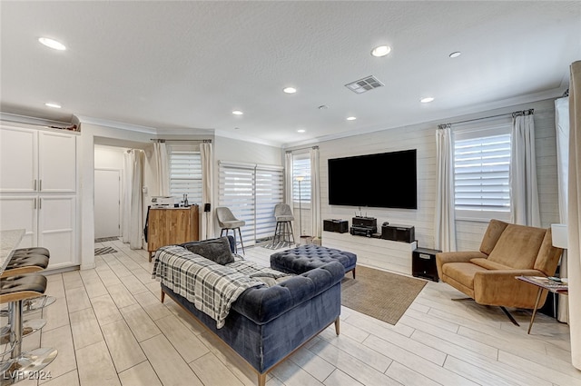 living room featuring a textured ceiling, crown molding, and light hardwood / wood-style floors