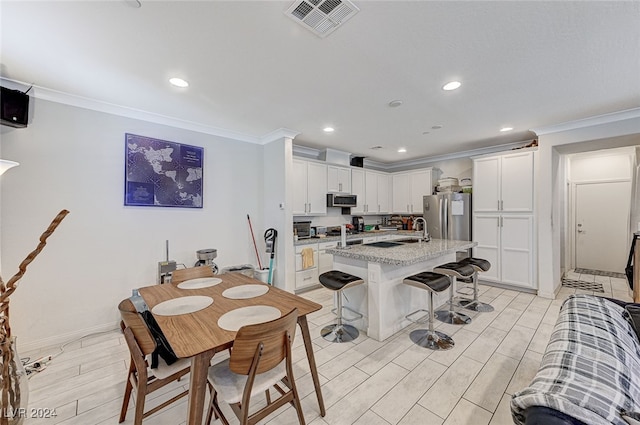 dining room featuring sink, light hardwood / wood-style floors, and ornamental molding