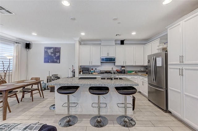 kitchen featuring white cabinets, an island with sink, appliances with stainless steel finishes, and extractor fan