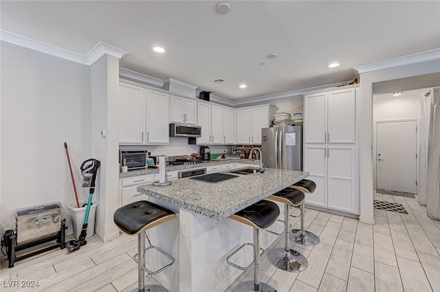 kitchen with light stone counters, sink, an island with sink, a kitchen breakfast bar, and appliances with stainless steel finishes