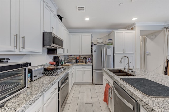 kitchen featuring white cabinets, stainless steel appliances, light wood-type flooring, and sink