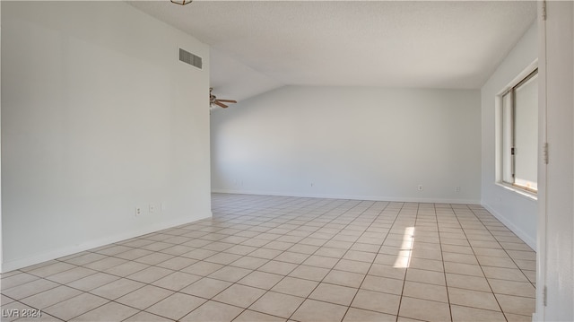 tiled empty room with vaulted ceiling, a textured ceiling, and ceiling fan