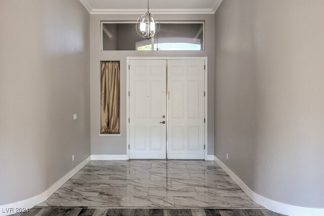 foyer with ornamental molding and an inviting chandelier