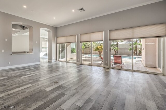 unfurnished living room with wood-type flooring, ornamental molding, and ceiling fan