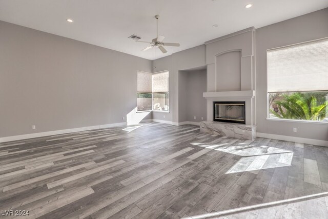 unfurnished living room with ceiling fan, a wealth of natural light, and wood-type flooring