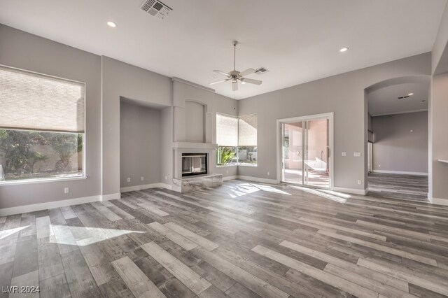 unfurnished living room with ceiling fan, a large fireplace, and wood-type flooring