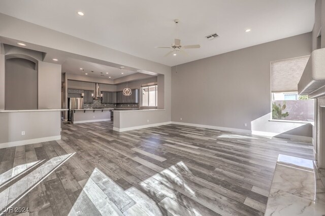 unfurnished living room with ceiling fan, hardwood / wood-style flooring, and plenty of natural light