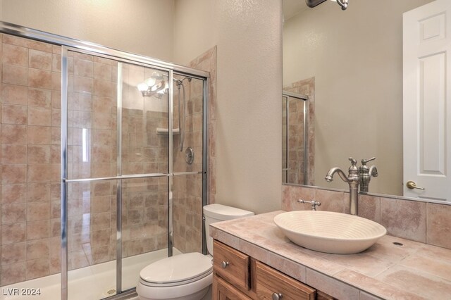 bathroom featuring a shower with shower door, vanity, and toilet