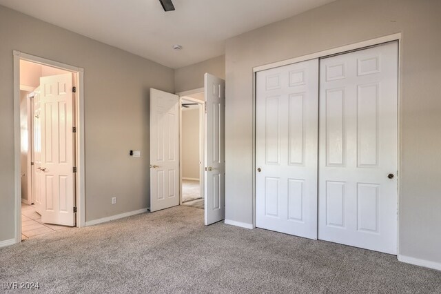 unfurnished bedroom with ceiling fan, a closet, and light carpet