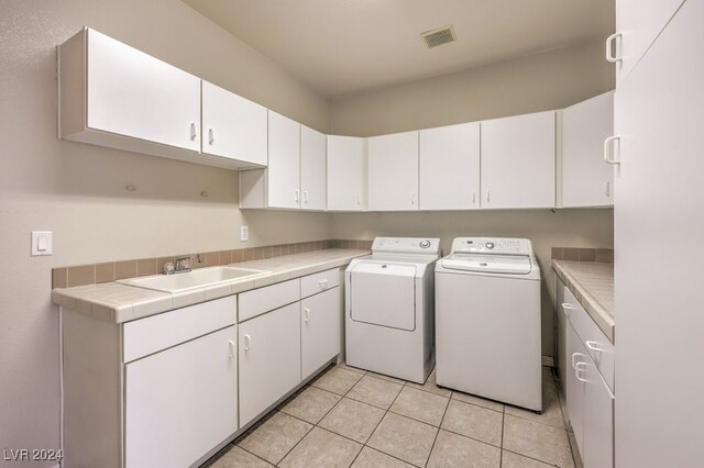 laundry room featuring light tile patterned flooring, washer and clothes dryer, sink, and cabinets