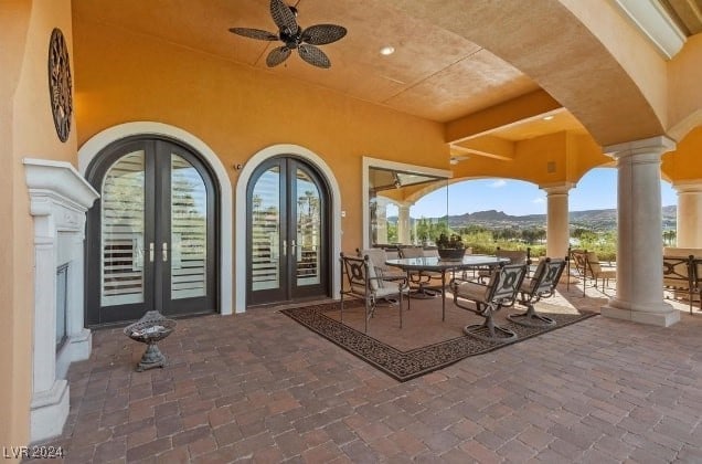 view of patio / terrace featuring a mountain view, ceiling fan, and french doors