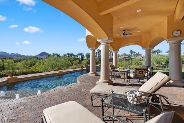 view of pool featuring ceiling fan, a mountain view, and a patio area