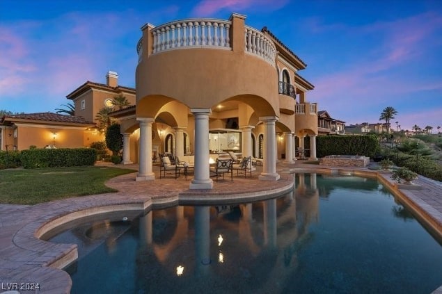 pool at dusk featuring a patio