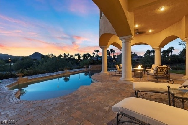 pool at dusk featuring a mountain view and a patio area