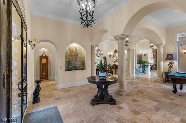 foyer entrance with a towering ceiling, ornate columns, crown molding, and pool table