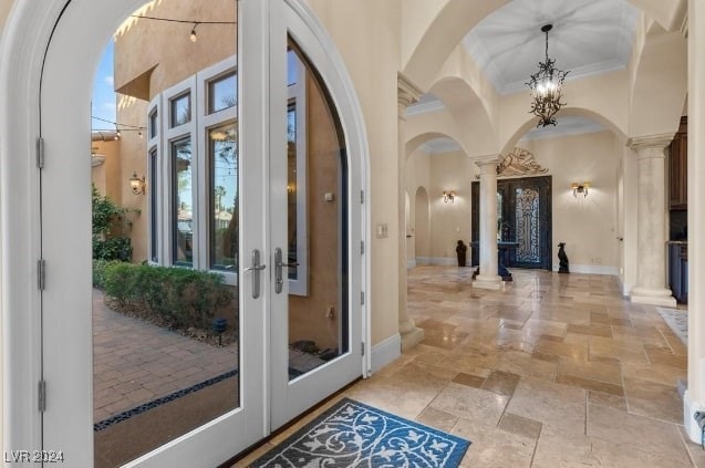 entrance foyer featuring french doors, crown molding, and decorative columns