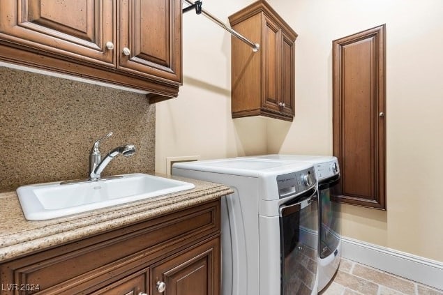 laundry room featuring sink, washing machine and clothes dryer, and cabinets