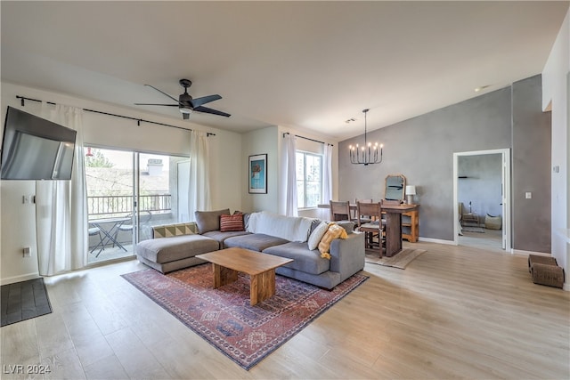 living room featuring ceiling fan with notable chandelier, light wood-type flooring, and lofted ceiling