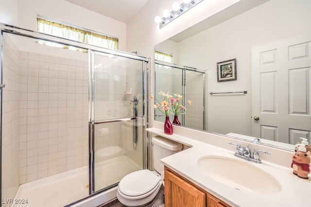 bathroom featuring vanity, toilet, and a shower with door