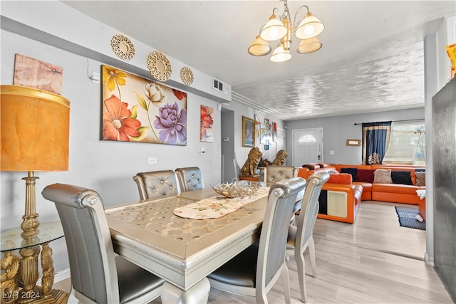 dining room with a textured ceiling, light hardwood / wood-style flooring, and a chandelier