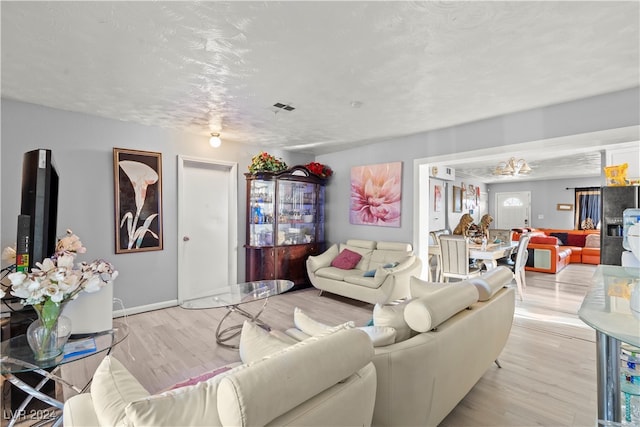 living room featuring light wood-type flooring and a textured ceiling