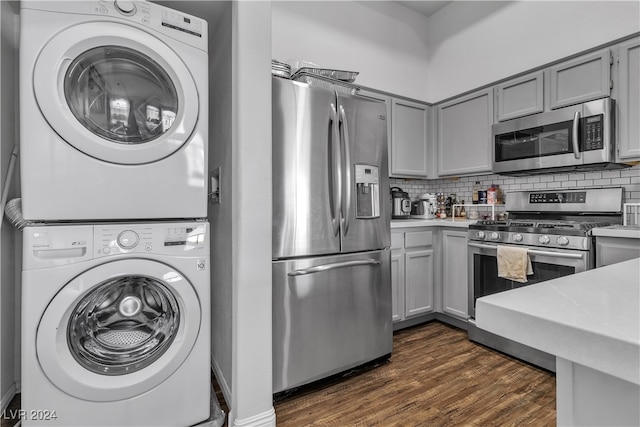 kitchen featuring gray cabinets, stacked washer / dryer, stainless steel appliances, and dark hardwood / wood-style flooring