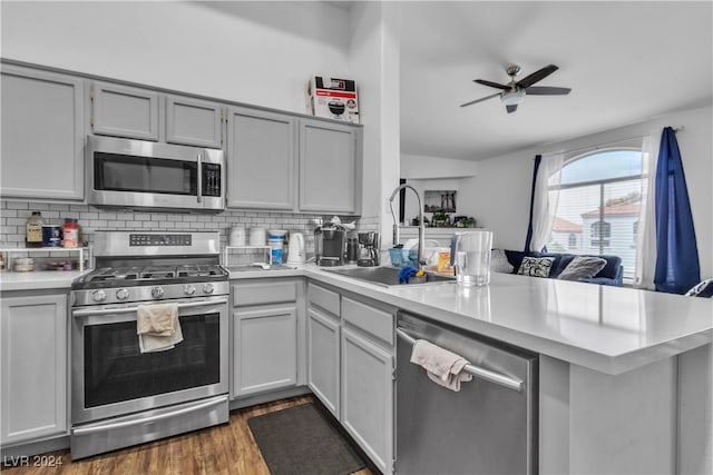 kitchen featuring gray cabinets, dark hardwood / wood-style flooring, sink, kitchen peninsula, and appliances with stainless steel finishes