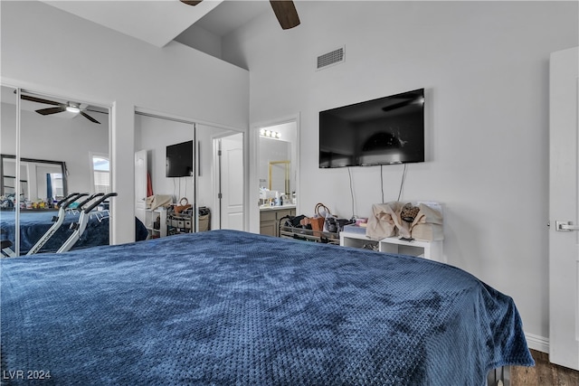 bedroom with hardwood / wood-style flooring, ensuite bath, ceiling fan, and a towering ceiling