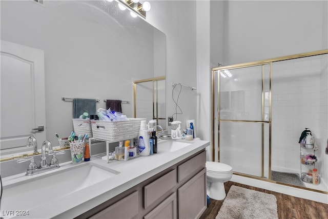 bathroom featuring hardwood / wood-style floors, vanity, a shower with shower door, and toilet