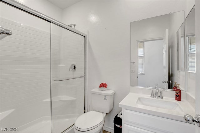 bathroom with a healthy amount of sunlight, a shower with door, vanity, and toilet