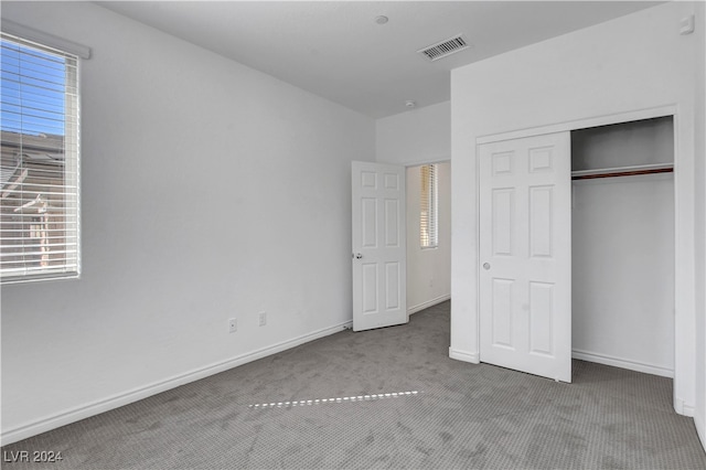 unfurnished bedroom featuring light carpet and a closet